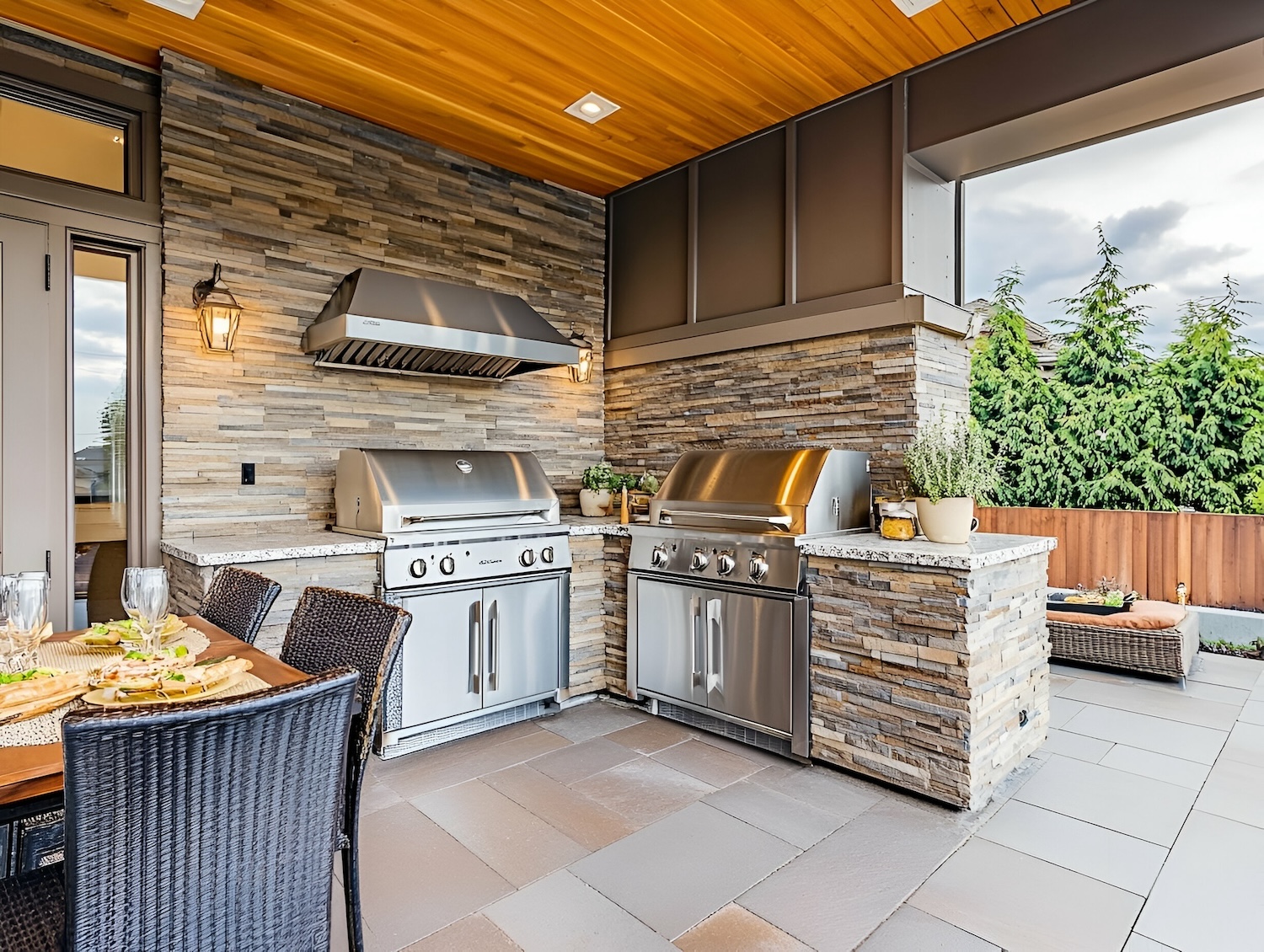 Modern outdoor kitchen with grills, stone accents, and dining area for entertaining. Maximizing-Your-Outdoor-Space-Patio-and-Deck-Trends-for-2025